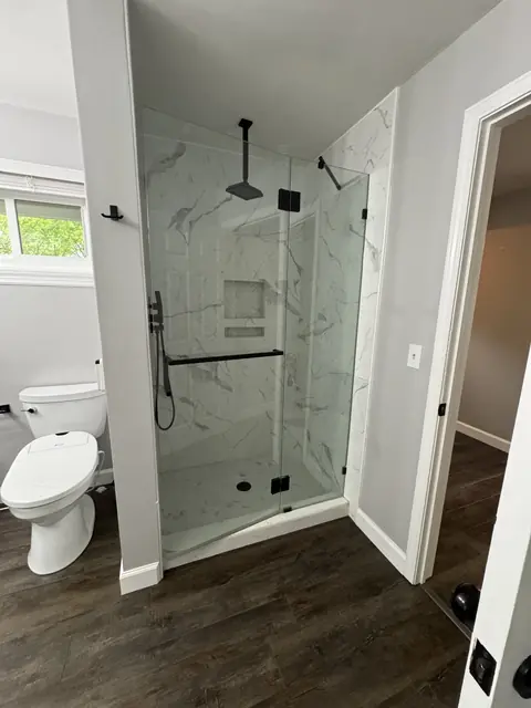 Clean glass shower enclosure and bright bathroom after professional cleaning