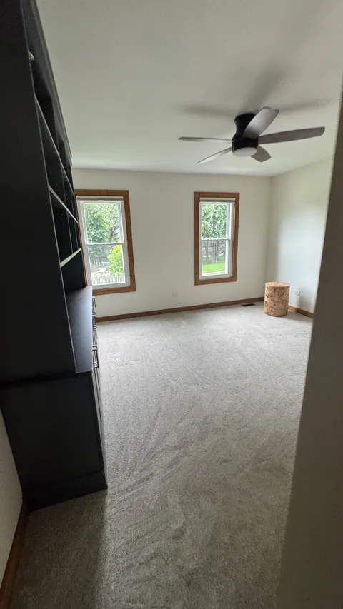 Bedroom with vacuumed carpet, a dusted ceiling fan and clean window trim
