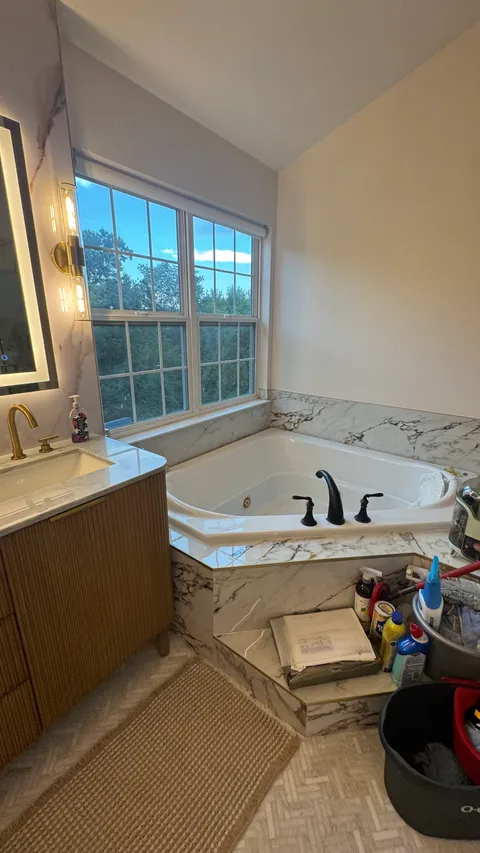 Corner soaking tub and marble surround scrubbed clean beside a bright window
