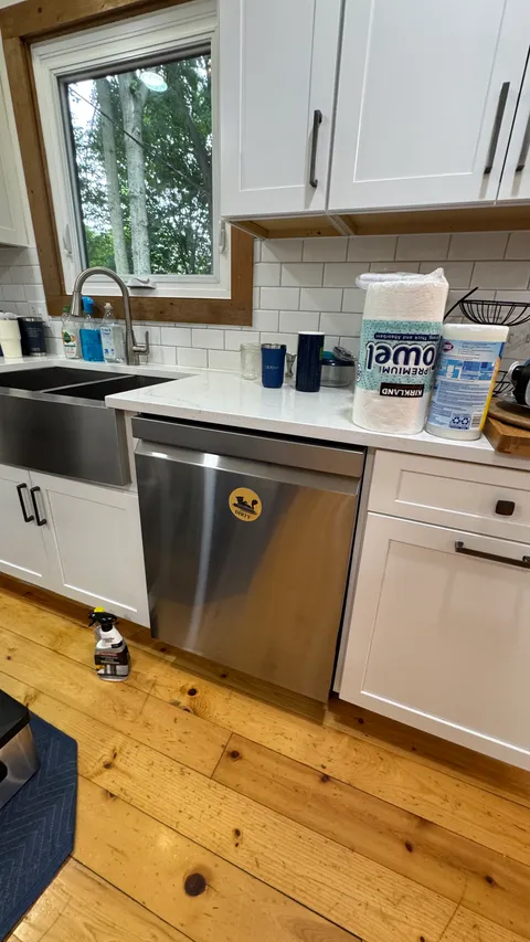 Polished stainless dishwasher and clear countertop above freshly mopped wood floors