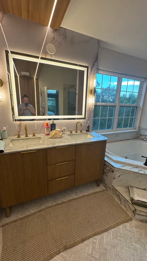 Cleaned double vanity with streak-free lighted mirror and polished gold fixtures