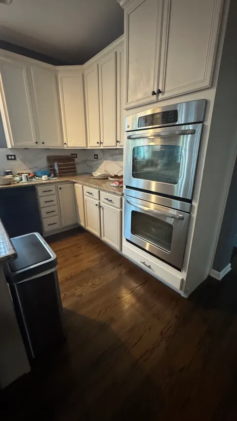Clean white kitchen cabinets and stainless double wall oven with mopped floors