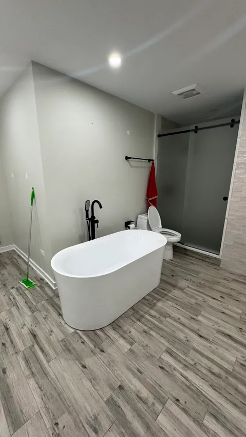 Freestanding soaking tub and mopped tile floor in a freshly cleaned bathroom