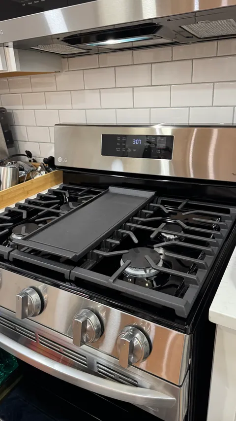 Polished stainless gas cooktop with a clean griddle and grease-free burner grates