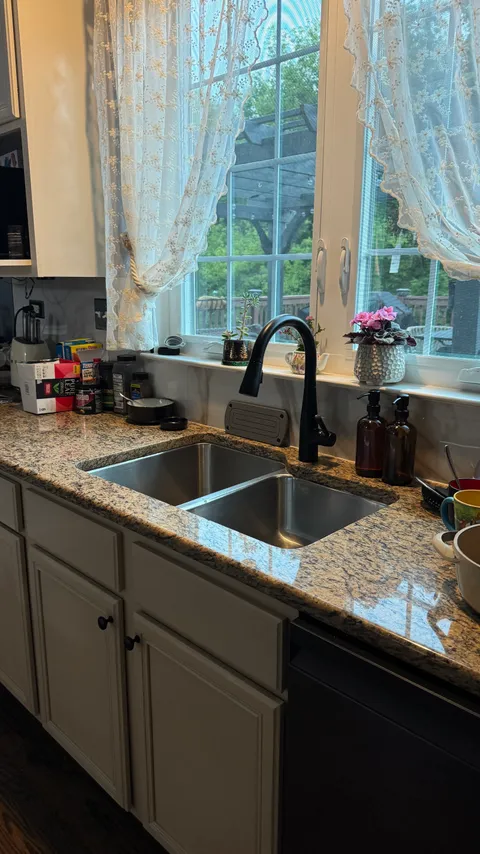 Polished stainless steel sink and granite countertops in a cleaned kitchen