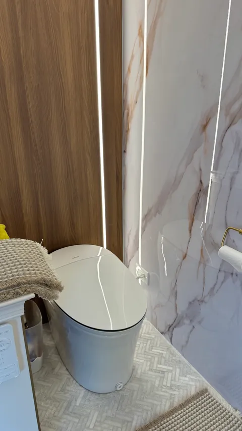 Sanitized toilet in a marble and wood bathroom with polished herringbone tile floor