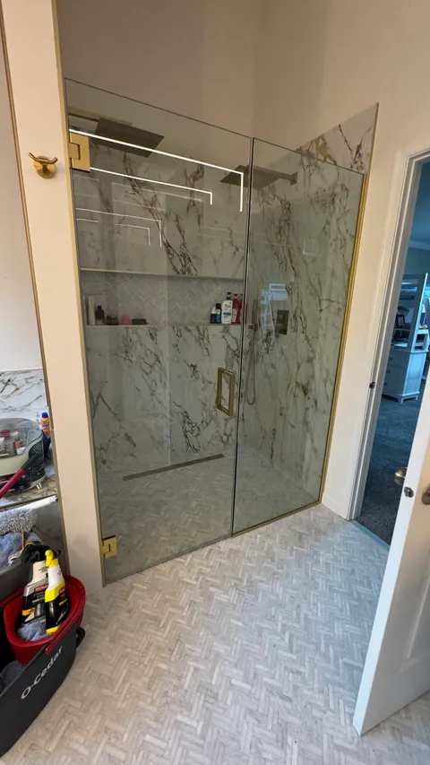 Streak-free glass shower doors and marble tile walls after professional cleaning