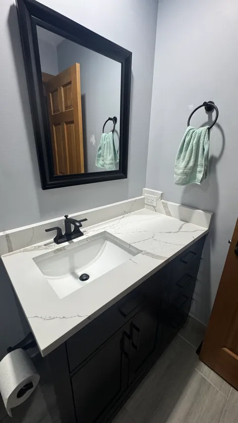 Powder room vanity with a wiped quartz top, clean sink and spotless mirror