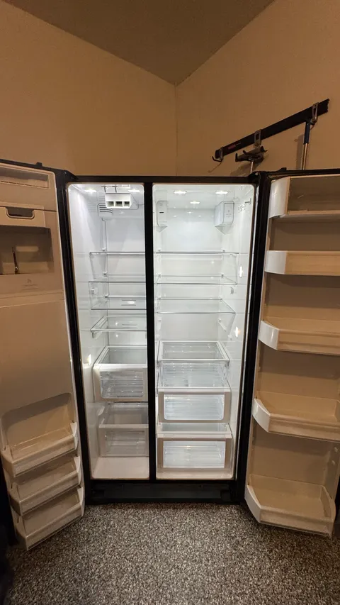 Emptied side-by-side refrigerator with spotless shelves and clear crisper drawers